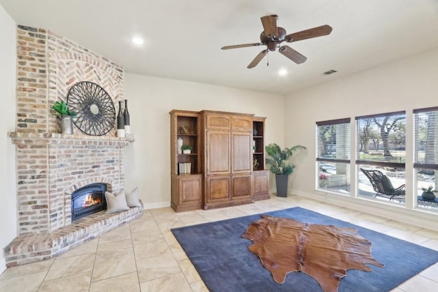 living room with a brick fireplace, light tile patterned floors, and ceiling fan