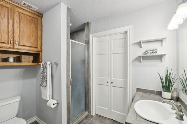 bathroom with an enclosed shower, vanity, a textured ceiling, tile patterned floors, and toilet