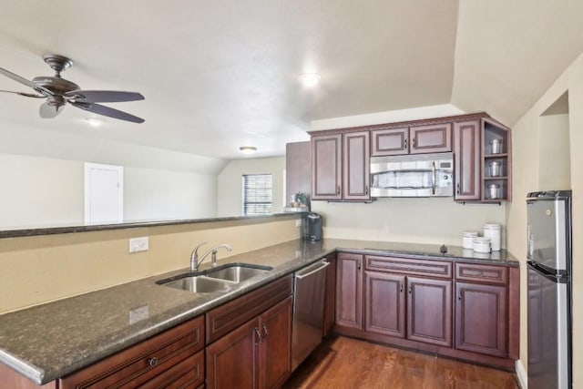 kitchen featuring lofted ceiling, sink, dark stone countertops, kitchen peninsula, and stainless steel appliances