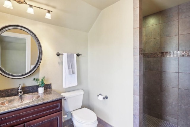 bathroom featuring vanity, toilet, and a tile shower