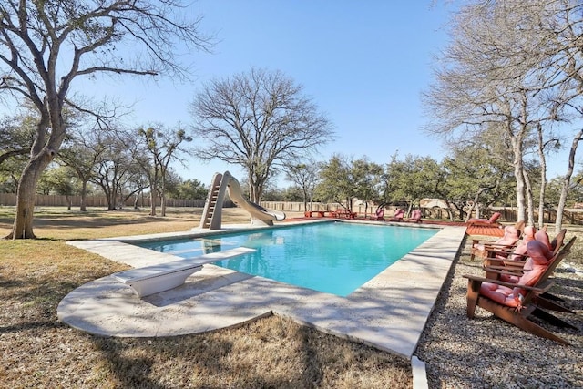 view of pool featuring a diving board and a water slide