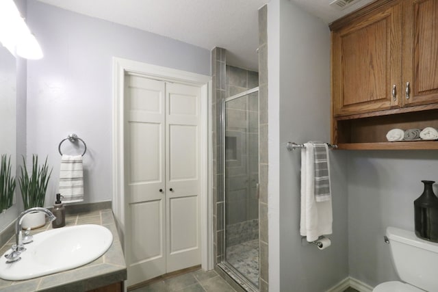 bathroom featuring toilet, a shower with door, and sink