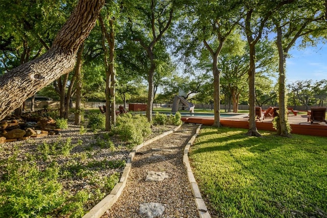 view of community featuring a deck, fence, and a lawn