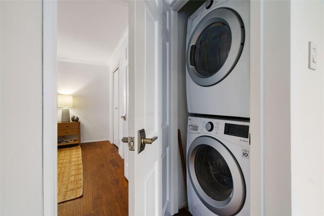 clothes washing area featuring dark wood-style flooring, stacked washer / drying machine, and laundry area