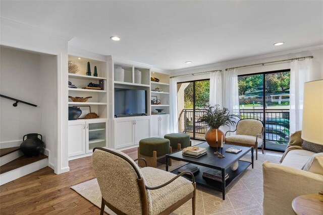 living area featuring wood finished floors, recessed lighting, and crown molding
