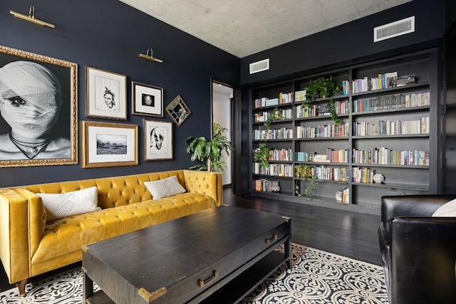 sitting room with wood-type flooring and built in shelves