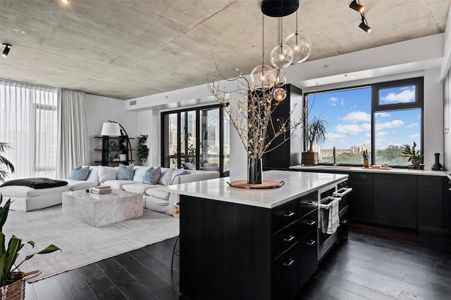 kitchen featuring pendant lighting, dark hardwood / wood-style floors, a center island, oven, and a chandelier