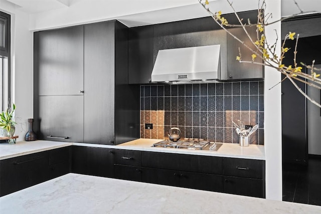 kitchen featuring wall chimney range hood, backsplash, and stainless steel gas stovetop