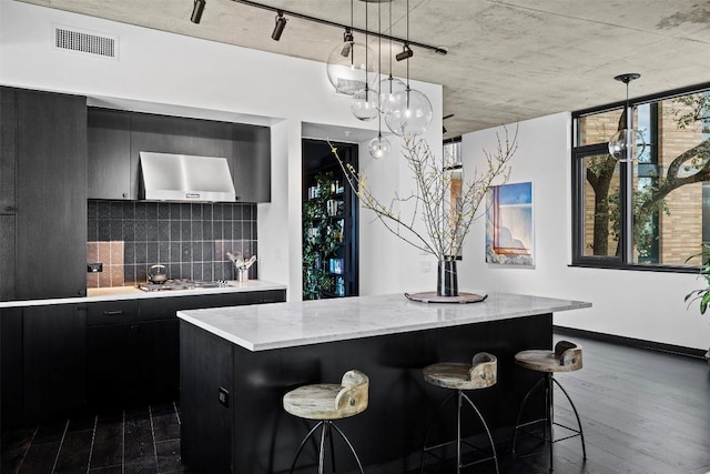 kitchen with hanging light fixtures, a kitchen island, extractor fan, and a kitchen bar