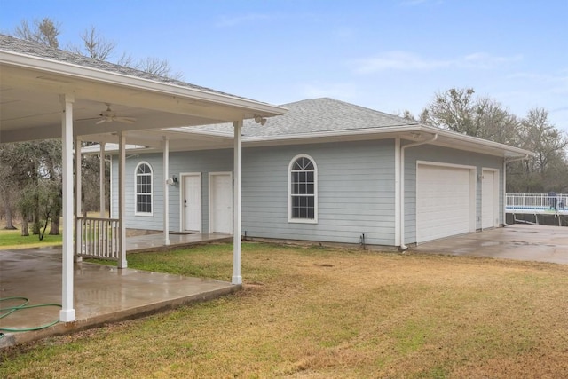 view of side of home with a garage, a carport, ceiling fan, and a lawn