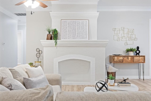 living room featuring ceiling fan, ornamental molding, and light wood-type flooring