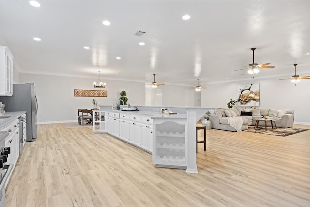 kitchen featuring white cabinetry, crown molding, a kitchen breakfast bar, and light wood-type flooring