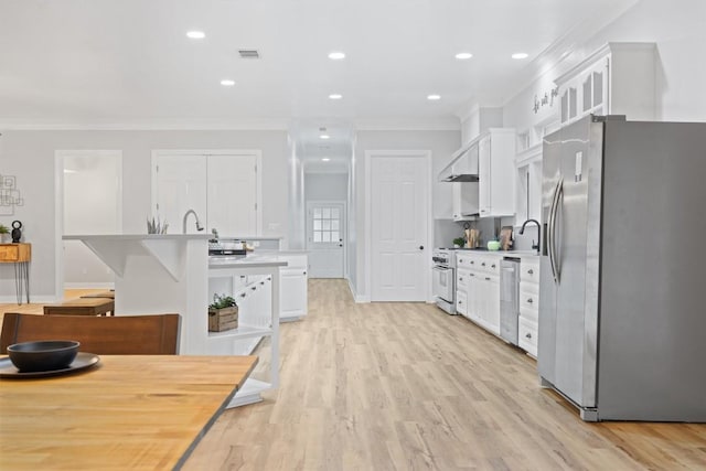 kitchen with light wood-type flooring, ornamental molding, white cabinets, stainless steel appliances, and wall chimney range hood