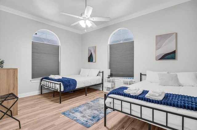 bedroom with ceiling fan, ornamental molding, multiple windows, and light wood-type flooring