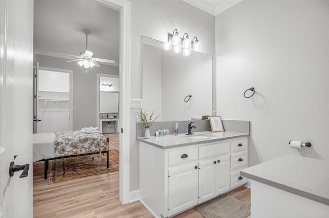 bathroom with hardwood / wood-style flooring, ornamental molding, vanity, and ceiling fan