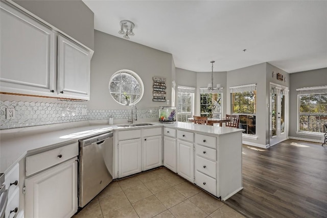 kitchen with white cabinetry, stainless steel dishwasher, kitchen peninsula, and sink