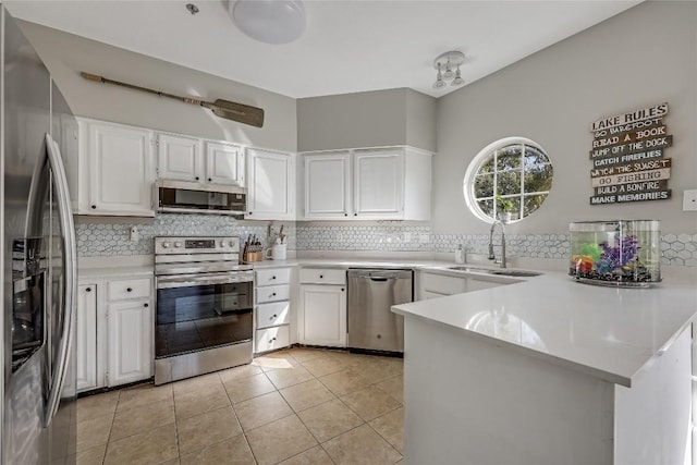 kitchen with sink, white cabinetry, stainless steel appliances, tasteful backsplash, and kitchen peninsula