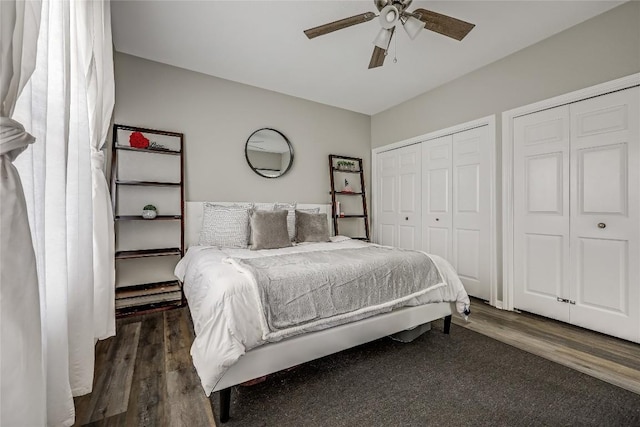 bedroom featuring multiple closets, dark hardwood / wood-style floors, and ceiling fan