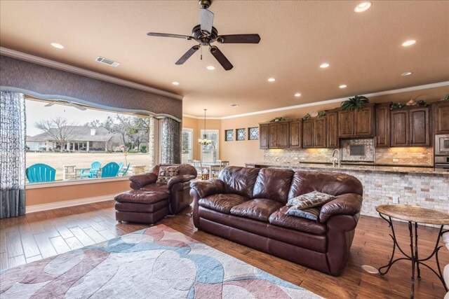 living room with hardwood / wood-style floors, ornamental molding, sink, and ceiling fan