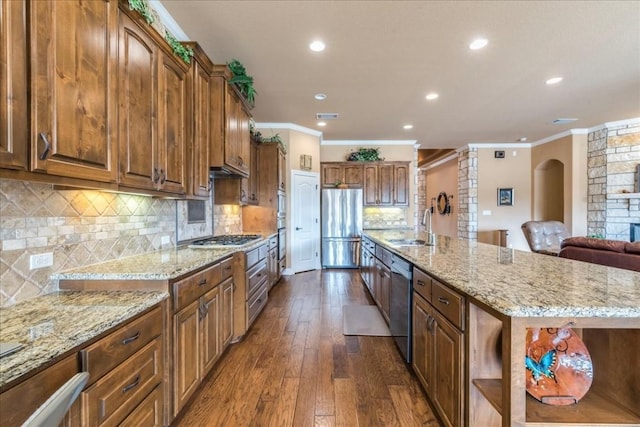 kitchen featuring stainless steel appliances, light stone countertops, sink, and a large island with sink