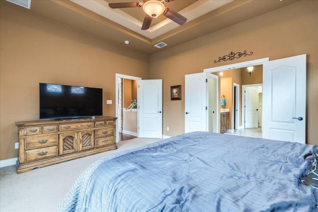 bedroom featuring connected bathroom, a tray ceiling, ceiling fan, and carpet flooring