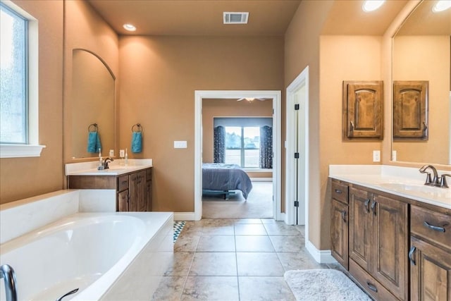 bathroom featuring vanity, a relaxing tiled tub, and tile patterned floors