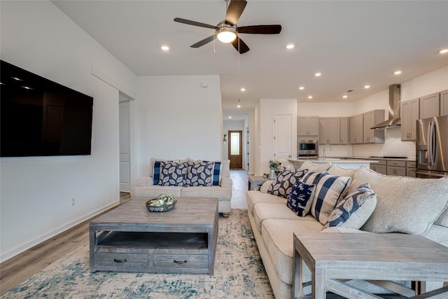 living room with sink, ceiling fan, and light hardwood / wood-style flooring