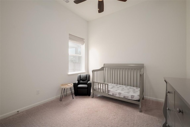 bedroom with vaulted ceiling, light colored carpet, a nursery area, and ceiling fan