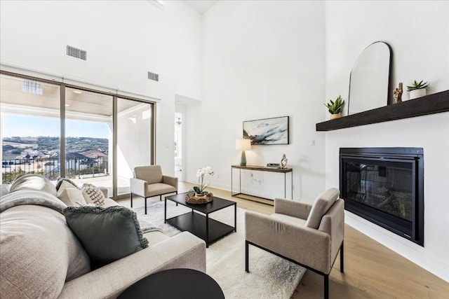 living room featuring a high ceiling and light hardwood / wood-style flooring