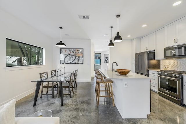 kitchen featuring pendant lighting, a kitchen island with sink, white cabinetry, high end appliances, and concrete floors