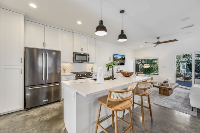 kitchen featuring white cabinetry, high quality appliances, concrete flooring, and an island with sink