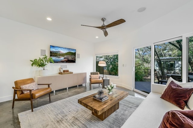 living room featuring a wealth of natural light, concrete floors, and ceiling fan