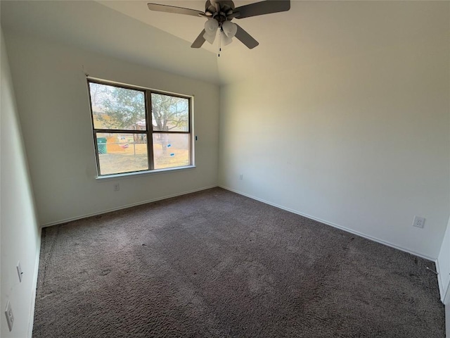 empty room featuring lofted ceiling, ceiling fan, and dark colored carpet