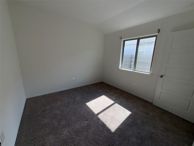 spare room with vaulted ceiling and dark carpet