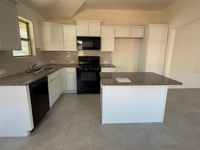 kitchen with dark stone countertops, sink, black appliances, and a kitchen island