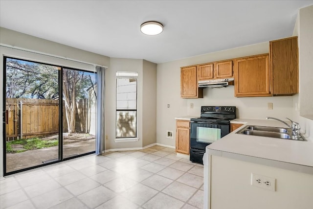 11901 Swearingen Dr Unit 37, Austin, TX 78758 - kitchen with black electric range, under cabinet range hood, light countertops, brown cabinetry, and light tile patterned flooring