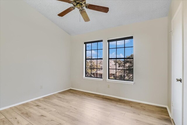 spare room featuring lofted ceiling, a textured ceiling, and light hardwood / wood-style flooring