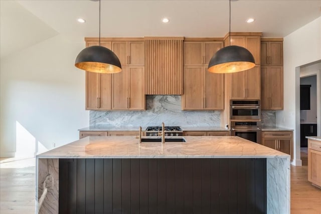 kitchen with light stone counters, a sink, light wood finished floors, and double oven