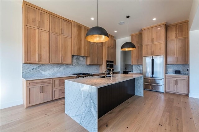kitchen with tasteful backsplash, a center island with sink, light stone counters, light wood finished floors, and stainless steel appliances