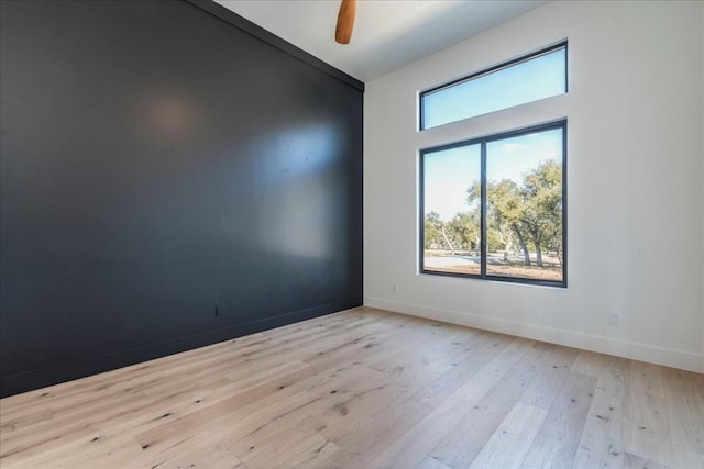 empty room with baseboards, ceiling fan, and wood finished floors