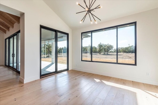 unfurnished room with light wood-style floors, baseboards, vaulted ceiling, and a chandelier