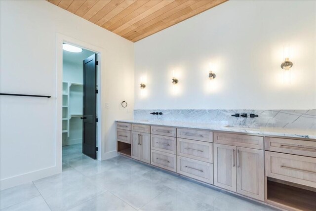 bathroom featuring a sink, wooden ceiling, tile patterned floors, and a walk in closet