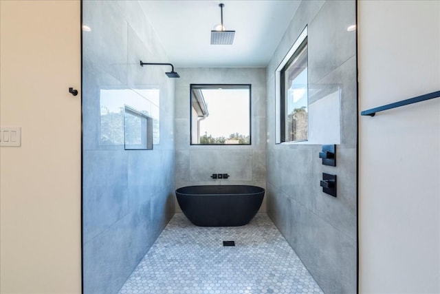 full bathroom featuring tile walls, tile patterned floors, a freestanding bath, and a tile shower