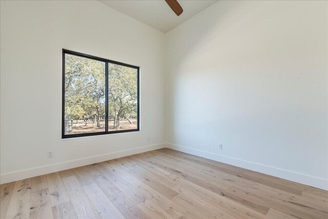empty room featuring baseboards, ceiling fan, and light wood finished floors