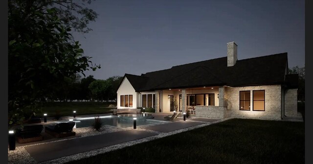 rear view of house with a lawn, a chimney, an outdoor pool, and stone siding