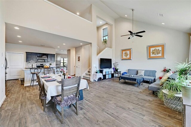 dining room featuring hardwood / wood-style floors, high vaulted ceiling, and ceiling fan