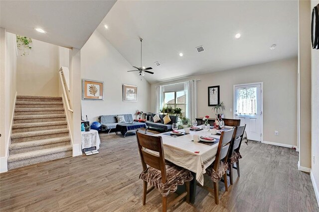 dining area with ceiling fan, high vaulted ceiling, and light hardwood / wood-style flooring