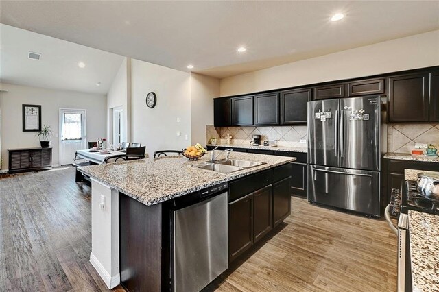 kitchen featuring an island with sink, appliances with stainless steel finishes, sink, and light hardwood / wood-style flooring