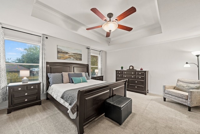 carpeted bedroom featuring a raised ceiling, ornamental molding, and ceiling fan