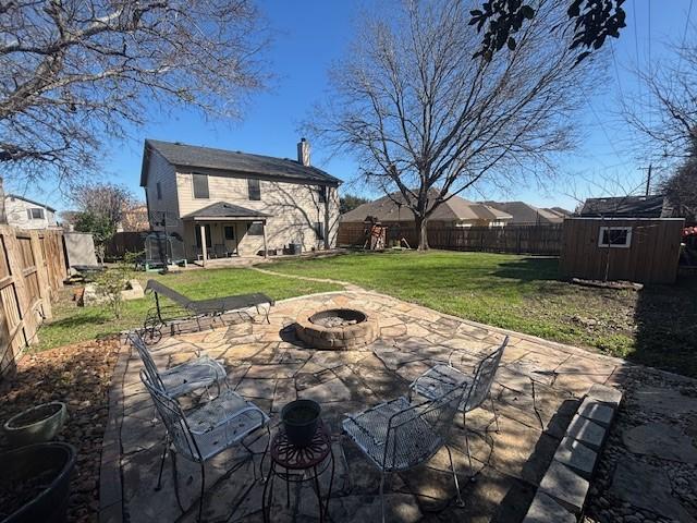 view of patio featuring an outdoor fire pit, a playground, and a shed